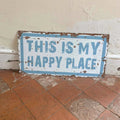 Vintage-style sign with 'This is my happy place' text on a tiled floor.